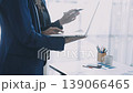 Two business people talk project strategy at office meeting room. Businessman discuss project planning with colleague at modern workplace while having conversation and advice on financial data report. 139066465