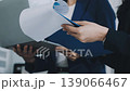 Two business people talk project strategy at office meeting room. Businessman discuss project planning with colleague at modern workplace while having conversation and advice on financial data report. 139066467