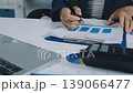 Two business people talk project strategy at office meeting room. Businessman discuss project planning with colleague at modern workplace while having conversation and advice on financial data report. 139066477
