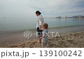 A mother and her young child share a tender moment, playing in the gentle waves on the beautiful beach of Malaga, creating cherished family memories. 139100242