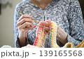 A close-up of a woman's hands enjoying crocheting with brightly colored yarn. 139165568