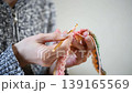 A close-up of a woman's hands enjoying crocheting with brightly colored yarn. 139165569