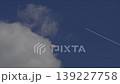 Airplane flying in blue sky leaving white contrail next to a fluffy cloud. 139227758
