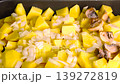 Close up of raw chopped potatoes with onions and mushrooms in a baking tray ready for roasting. 139272819