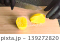 Slicing peeled potato on wooden cutting board with knife. Close up food preparation. 139272820