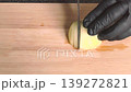 Chef in black gloves slicing fresh onion on wooden cutting board, cooking process close up. 139272821