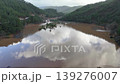 Muddy floodwaters of the Namnam River revealing surging over a concrete stepped weir surrounded by pine-forested hills in Koycegiz, Mugla, Turkey. Aerial drone view, moving backwards 139276007