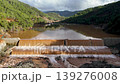 Muddy floodwaters of the Namnam River surging over a concrete stepped weir surrounded by pine-forested hills in Koycegiz, Mugla, Turkey. Aerial drone view, with moving forward 139276008
