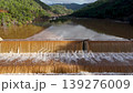 Muddy floodwaters of the Namnam River surging over a concrete stepped weir surrounded by pine-forested hills in Koycegiz, Mugla, Turkey. Aerial drone view with no movement 139276009