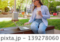 A woman sitting in the park with a laptop and working during the summer day 139278060