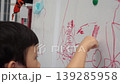 A child drawing on a whiteboard, creating a vivid piece of art with a red marker 139285958