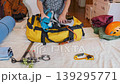 Woman packing duffel bag with climbing equipment and clothing at home, organizing gear for hiking or mountaineering trip, preparation process for outdoor adventure, active lifestyle concept 139295771