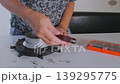 Person tightening bolts on softbox light mount using multitool, assembling studio lighting equipment at home or workshop, setup process for photography or video production, close up of hands 139295775