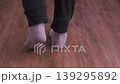 Rear view, person walking in socks along a dark hallway at home, calm indoor movement, quiet atmosphere, casual lifestyle moment in apartment interior. Indoor movement, daily routine, home lifestyle 139295892
