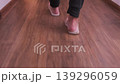 Rear view of person walking in flip flops along indoor apartment hallway with wooden floor, casual home movement, focus on footsteps and relaxed domestic lifestyle atmosphere 139296059