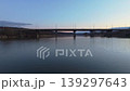 Smooth rightward aerial drone pan over riverside cityscape at sunset with reflections and warm illuminated buildings. Concept of calm urban evening atmosphere and harmony between architecture 139297643