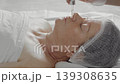 The hand of a cosmetologist applies rejuvenating oil to the face of an elderly woman with a pipette 139308635