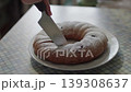 The hand of an elderly woman cuts a freshly baked pie on the kitchen table with a knife 139308637