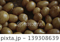A wooden kitchen spatula stirs potatoes frying in oil in a pan 139308639