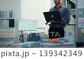 Thoughtful young Latin businessman stand with laptop analyzing data above paperwork stack. Hybrid work audit, digital transformation strategy, business corporate finance, executive decision concept. 139342349