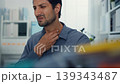Sick young Latin businessman touching neck with severe sore throat pain at office desk. Working while sick, flu virus, coughing infection, contagious fever, burnout, healthcare insurance concept. 139343487