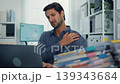 Young Latino businessman suffering shoulder pain and neck ache at office desk with computer. Office syndrome, muscle massage, overworked stress, bad posture, and health insurance injury concept. 139343684