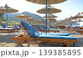 Empty sun loungers with blue cushions on a pebble 139385895
