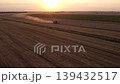 Harvesting wheat at sunset. Beautiful view of combine harvester working at the field of wheat in the evening 139432517