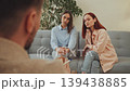two women sitting on couch during therapy session, talking with counselor, showing serious conversation and psychological support 139438885