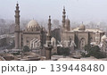 Historic mosques with tall minarets and grand domes dominate the hazy Cairo cityscape, Egypt, showcasing stunning Mamluk Islamic architecture from the medieval period. 139448480