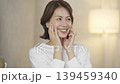 A middle-aged woman doing skin care in the living room at night 139459340