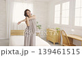 A middle-aged woman stretching in her bedroom. 139461515