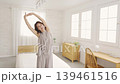A middle-aged woman stretching in her bedroom. 139461516