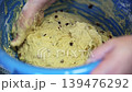 Kneading Raisins into Yeast Dough by Hand in a Blue Basin 139476292
