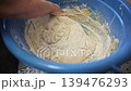 Mixing Flour and Liquid Batter by Hand in a Large Blue Basin 139476293