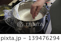 Whisking White Liquid Mixture in a Large Metal Pot on a Stove 139476294