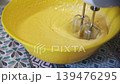 Beating Egg and Sugar Batter with Electric Mixer in a Yellow Bowl 139476295