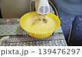 Whisking Thick Cake Batter with Electric Mixer in a Yellow Bowl 139476297