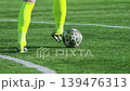 Football Player Dribbling a Soccer Ball on Green Grass Field 139476313