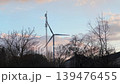 Wind Turbine with Spinning Blades and Cell Tower at Sunset, Silhouetted Agai 139476455