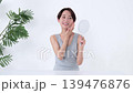 一位女士正在鏡子前檢查自己的皮膚。 139476876