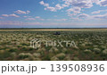 Aerial shot of an off-road vehicle driving through vast steppe landscape 139508936