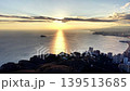 Golden Sunrise Over Coastal City Skyline, Low Sun Casting Long Shimmering Path Across Calm Bay, Soft Clouds 139513685