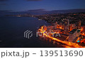 Vibrant Coastal Boulevard At Night, Drone Sweep Over Curving Shoreline Road Lit By Amber Streetlights, 139513690