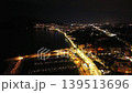 Aerial Night Waterfront Highway Lights Streak Along Coast, Drone Passes Over Busy Shorefront With Flowing 139513696