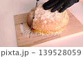 Baker in black gloves slicing a fresh loaf of homemade artisan sourdough bread. 139528059