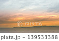 The island silhouette and the evening sea bathed in the orange glow of the setting sun. 139533388