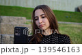 Lady taking selfportrait on park steps. Woman peacefully recording short social media video outdoors. Relaxed woman in casual attire capturing selfie for online content in park setting 139546163