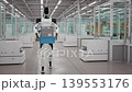 AI-powered Humanoid Robots Walking and Carrying Crates with Lithium-Ion Battery Modules in an Fully Automated Car Factory. Robotic Arms Assembling Electric Cars in the Background. 3d animation render 139553176