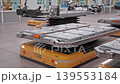 Rows of Lithium-Ion Battery Modules loaded on AGVs inside Fully Automated Modern Car Factory. AI-powered Humanoid Robots and Robotic Arms Assembling Electric Cars in Background. 3d animation render 139553184